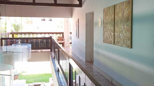 Interior espaçoso com teto alto, varanda com guarda-corpo e vista para o exterior.