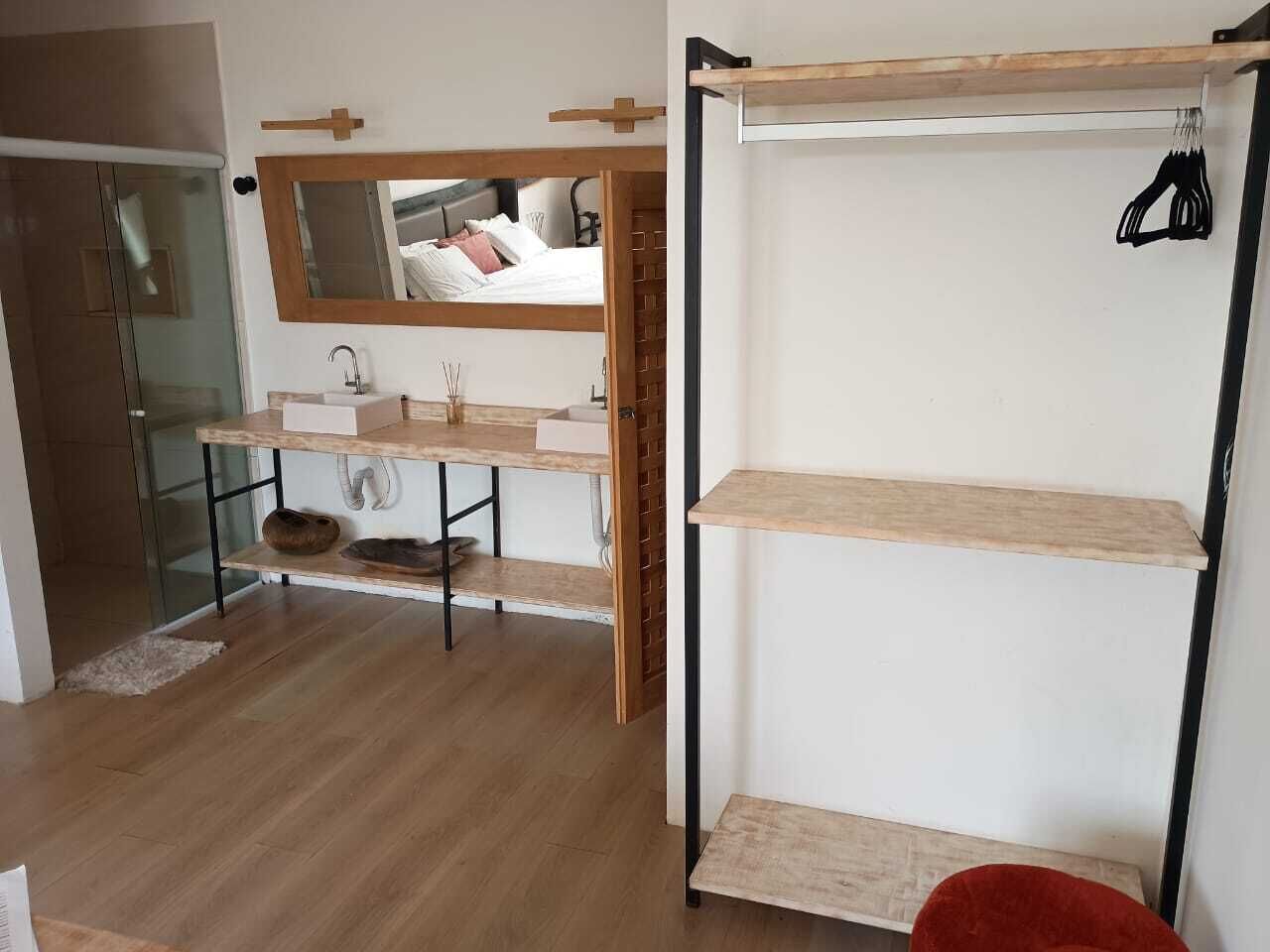 Un bany modern amb un tocador de fusta, un mirall i un moble prestatge encastat.