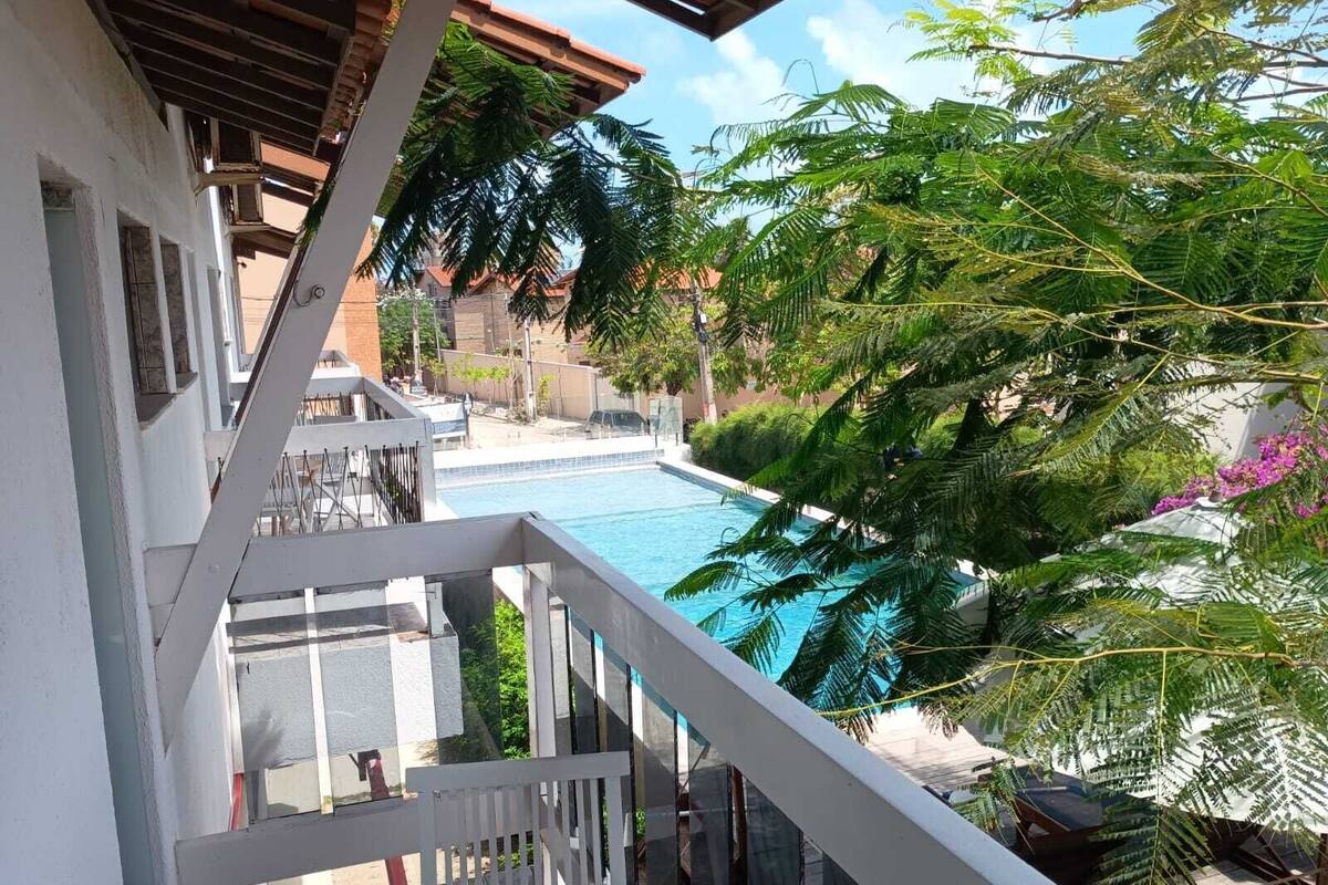 Une vue sur la piscine, avec une eau d’un bleu limpide, une balustrade blanche et une végétation luxuriante.