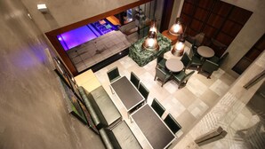 Un salón amplio con techos altos y varios arreglos de asientos, incluyendo sofás y mesas, además de una pieza decorativa central.