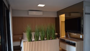 A modern living room with a sofa, a TV, and a wooden accent wall. - Grupo Vip Landscape Fortaleza (Fortaleza)