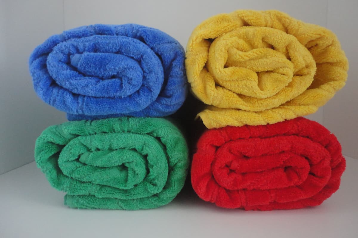 Four rolled towels in blue, yellow, green, and red colors.