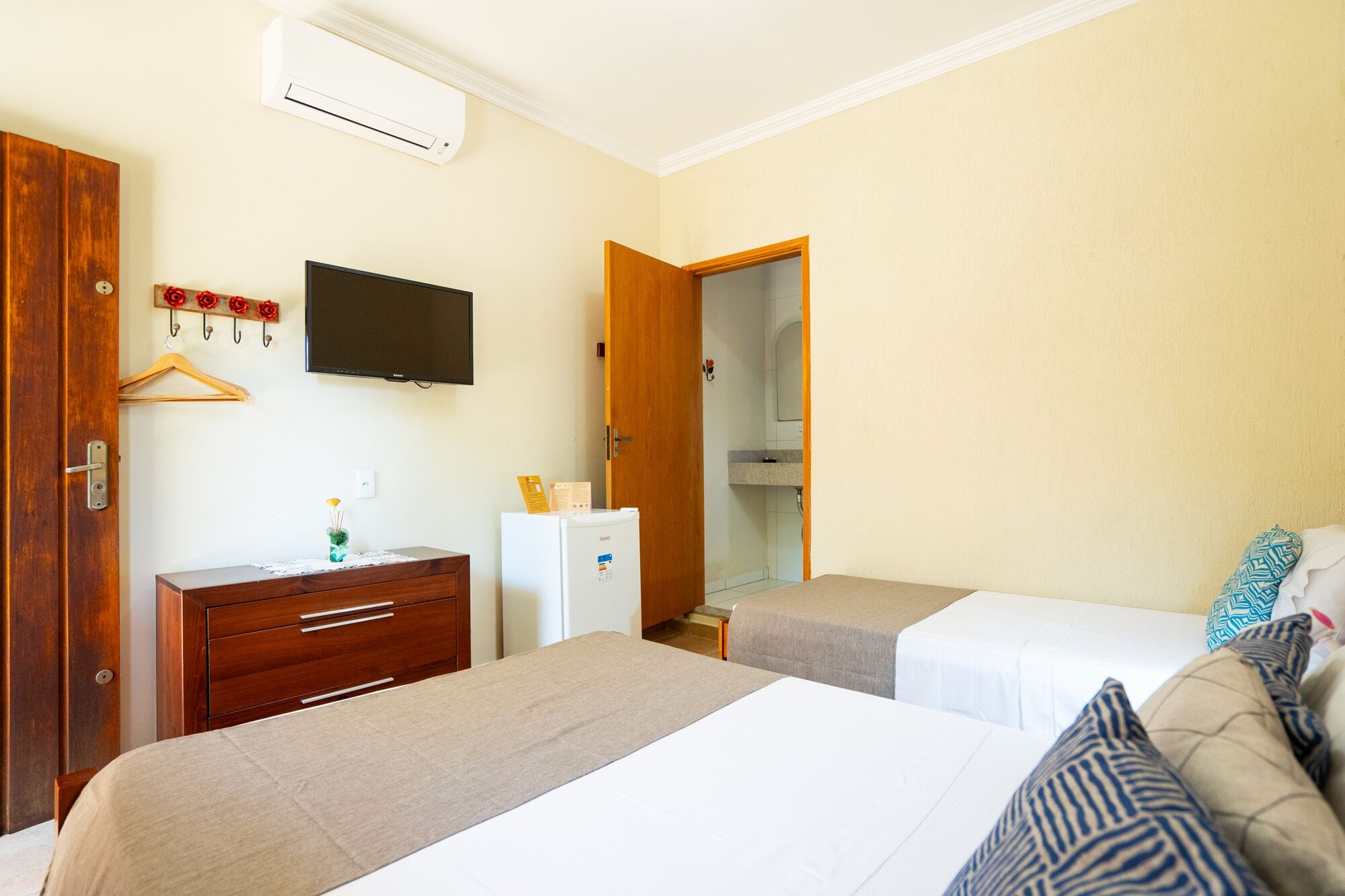 Camera d'albergo con due letti, una cassettiera, una televisione e un armadio.