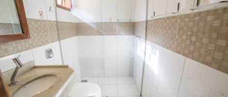 Une salle de bain équipée d’une douche, de toilettes, d’un lavabo et d’un miroir.