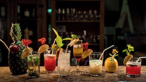 A variety of cocktails on a bar counter with a blurred background of shelves. - Pousada Galeria Artes (Bonito)