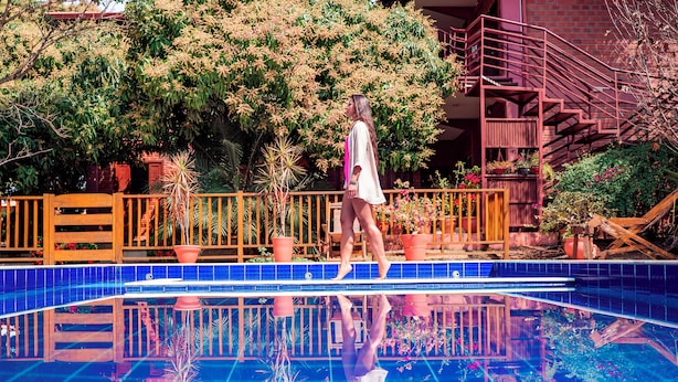 A pool with a tiled edge and a wooden deck. - Pousada Galeria Artes (Bonito)
