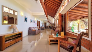 A spacious living area with a high ceiling, wooden beams, and large windows offering views of the outdoors. - Pousada Galeria Artes (Bonito)