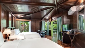 A hotel room with two beds, a desk, a TV, and a balcony with curtains. - Chachagua Rainforest Hotel & Hot Springs (Peñas Blancas)