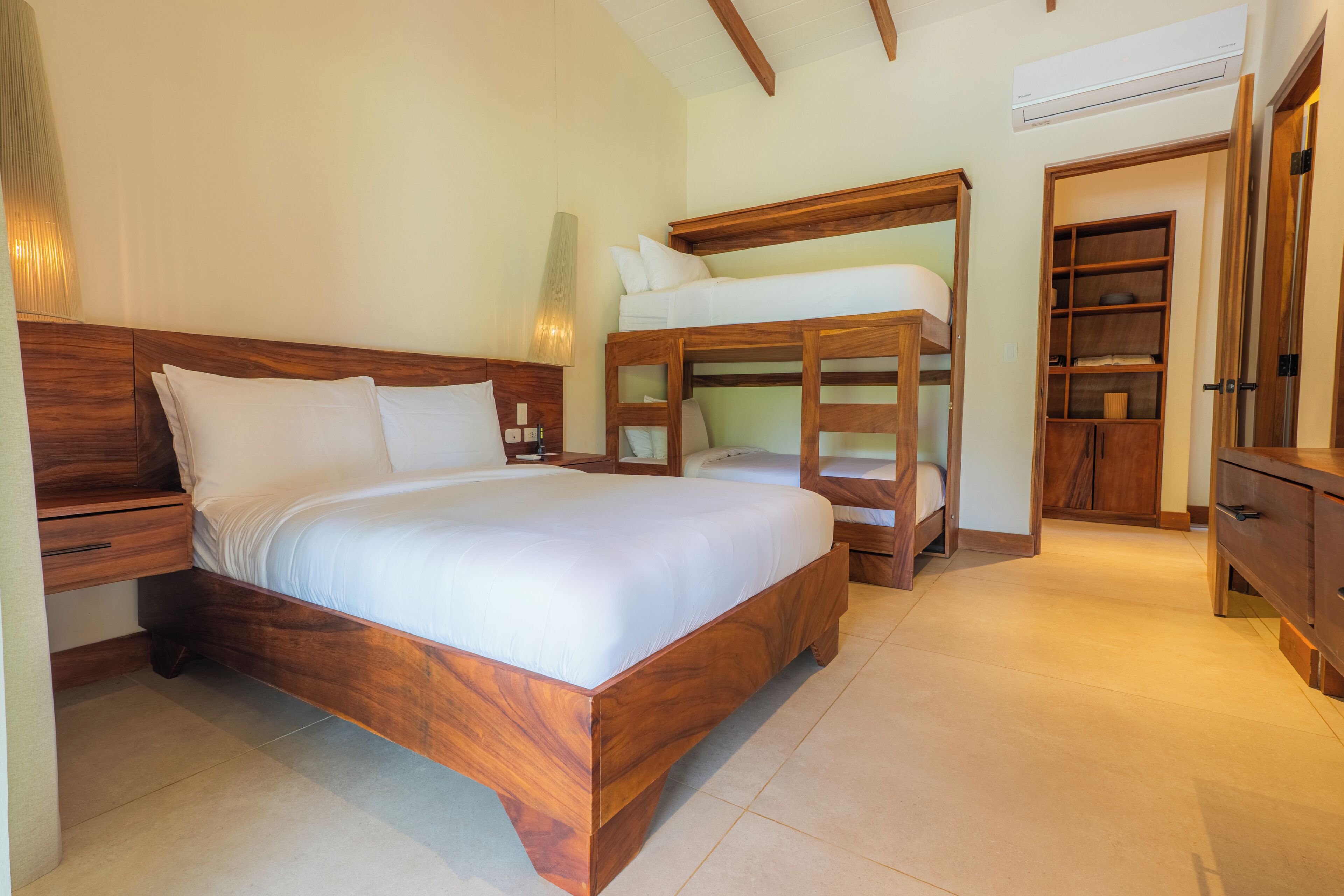 A bedroom with a wooden bed, a bunk bed, a wardrobe, and a nightstand.
