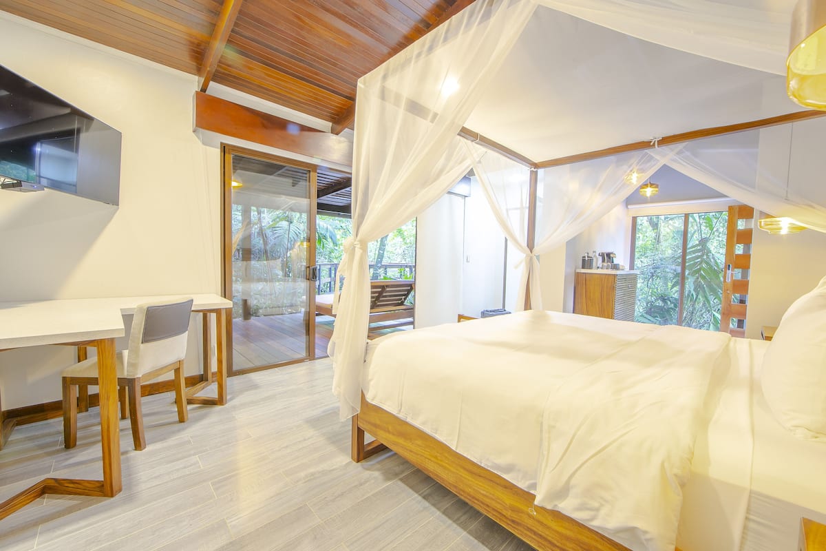 A bedroom with a canopy bed, a desk, and a chair.