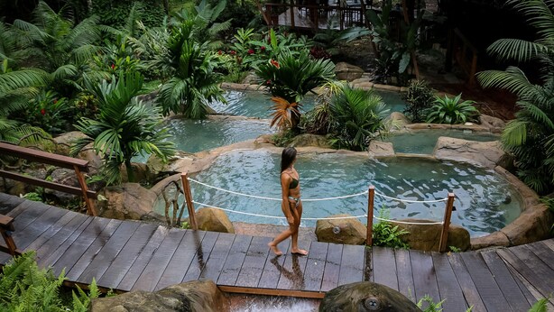 A wooden deck with a rope barrier leading to a pool area surrounded by tropical vegetation. - Chachagua Rainforest Hotel & Hot Springs (Peñas Blancas)