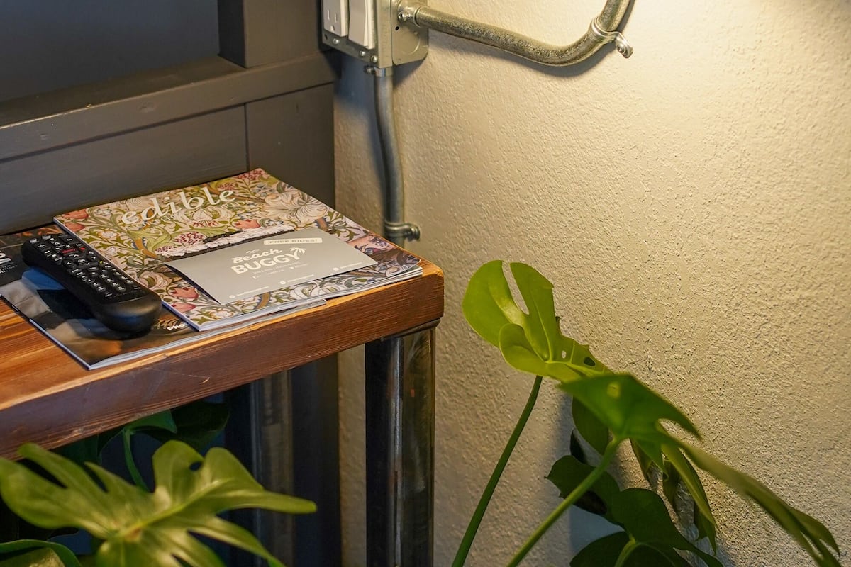 A bedside table with a lamp, a remote control, and a decorative item.