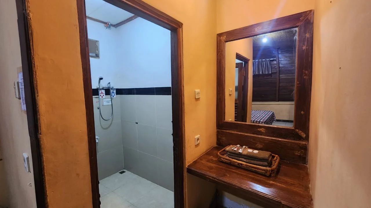 A bathroom with a shower, a wooden vanity with a mirror, and a towel rack.