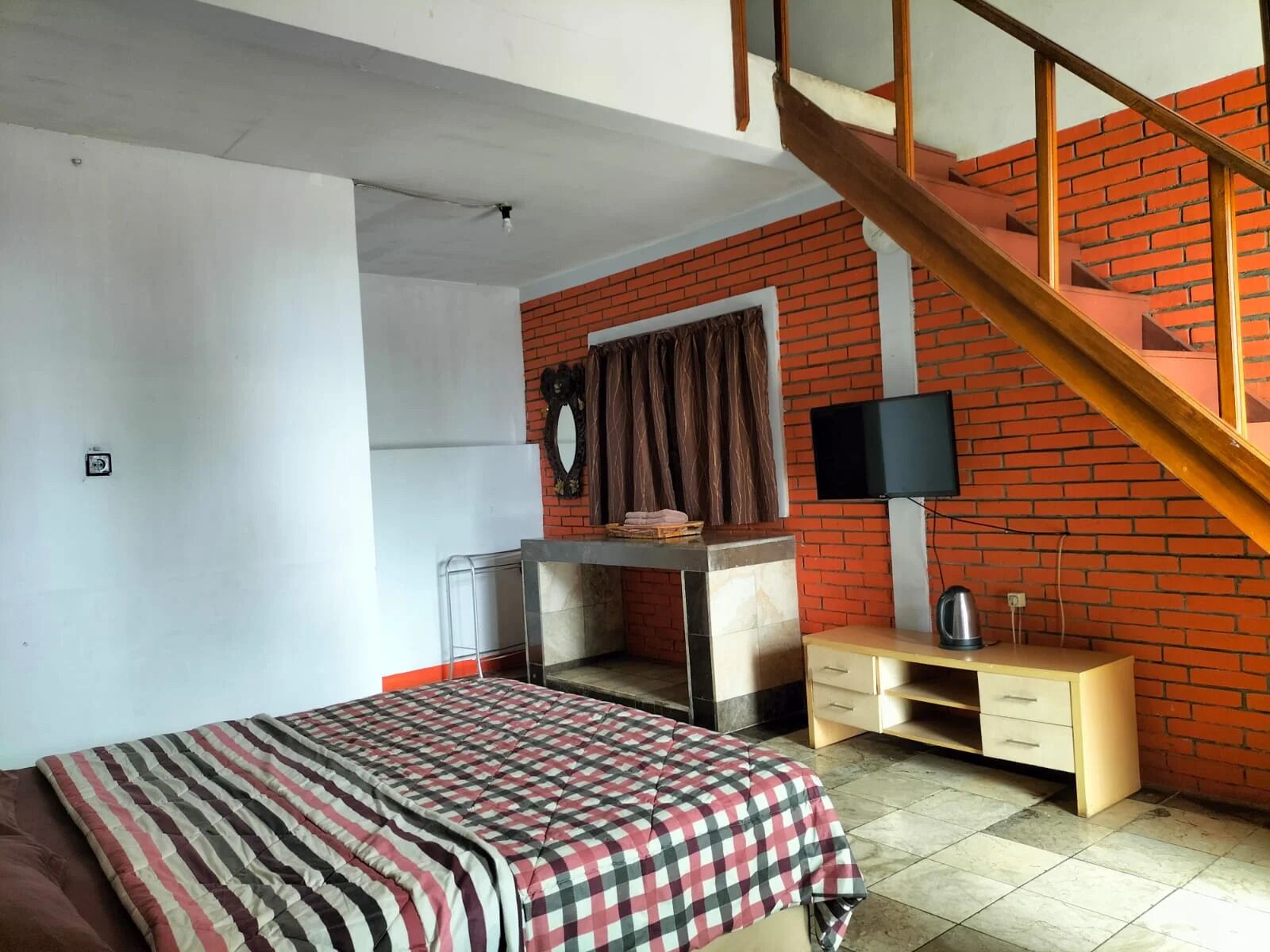 Een slaapkamer met een bed, een bureau, een stoel, een televisie en een trap.