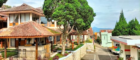 Um edifício tradicional com telhado de telhas, parede de pedra e um pequeno jardim com plantas em vasos.