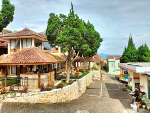 A traditional building with a tiled roof, a stone wall, and a small garden area with potted plants.