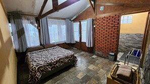 A bedroom with a bed, curtains, a brick wall, and a window. - Nur Alam Hotel Lembang (Lembang)
