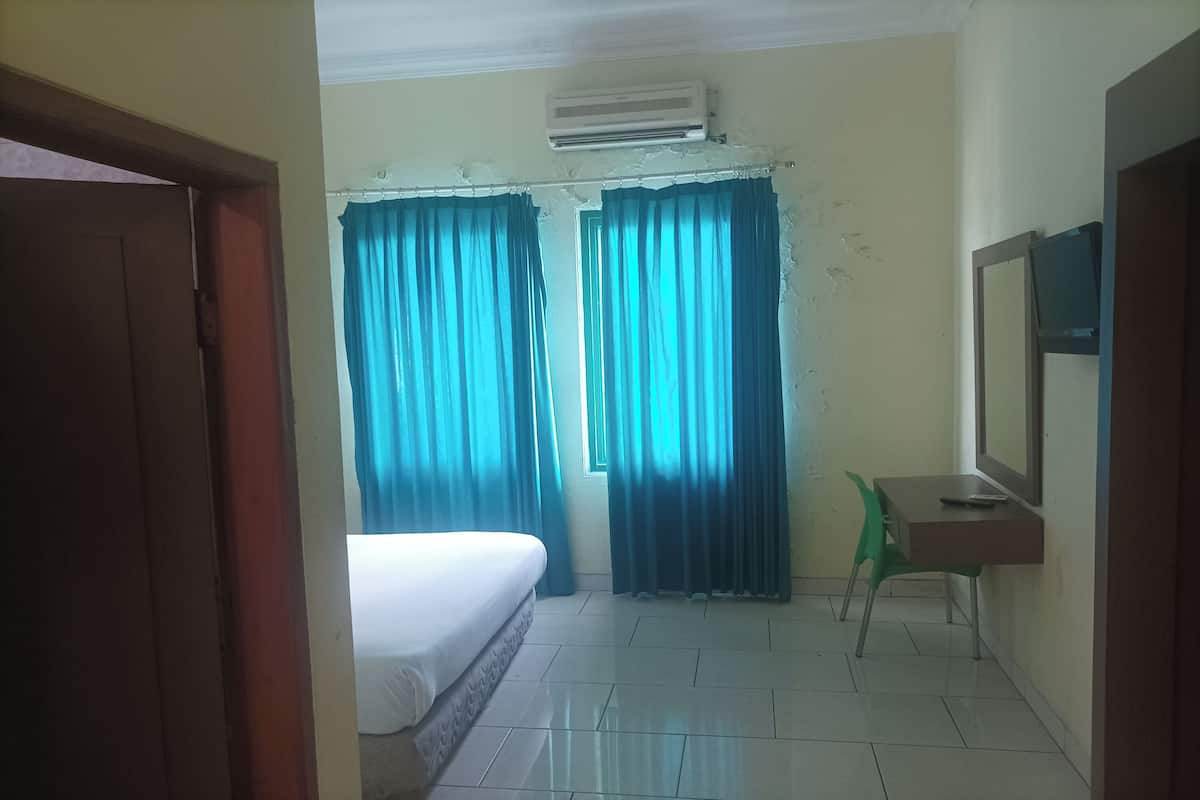 A room with a bed, a desk with a chair, a television, and curtains.