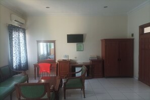 A room with a dining table, chairs, a sofa, a TV, and a wardrobe.