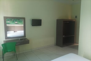 A room with a bed, a green chair, a TV on a wall, and a wardrobe. - Permata Hijau by Zuzu (North Cirebon)