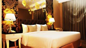 A hotel room with a large bed, two bedside tables with lamps, a decorative headboard, and curtains.