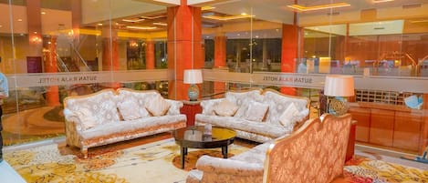 A lobby with two sofas, a coffee table, and a patterned rug.