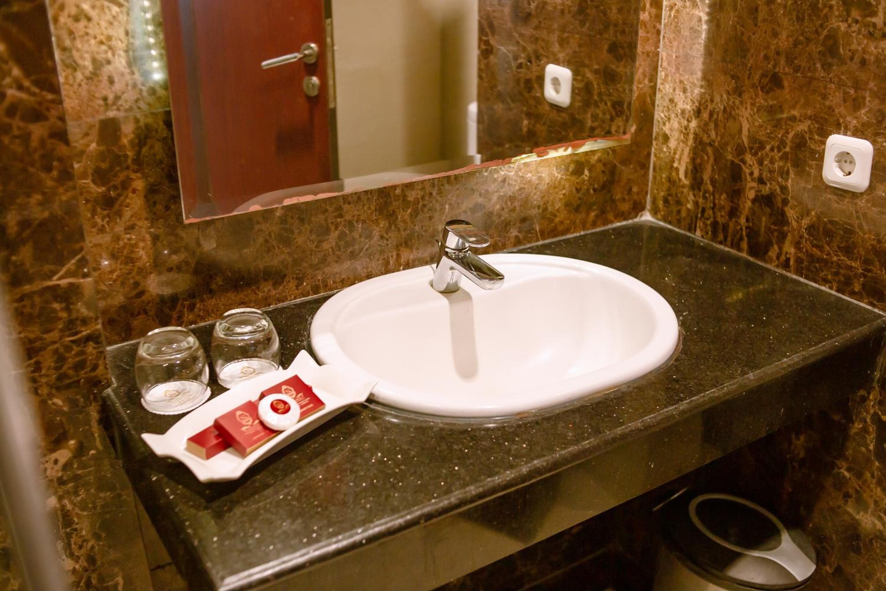 Un baño con lavamanos de mármol, un espejo y un perchero para toallas.