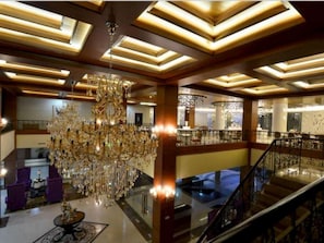 A grand lobby with a large chandelier, a staircase, and a high ceiling with recessed lighting. - Sutan Raja Hotel and Convention Cen (Soreang)