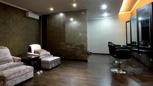 A modern interior with a seating area, a mirror, and a wall with a textured pattern. - Sutan Raja Hotel and Convention Cen (Soreang)