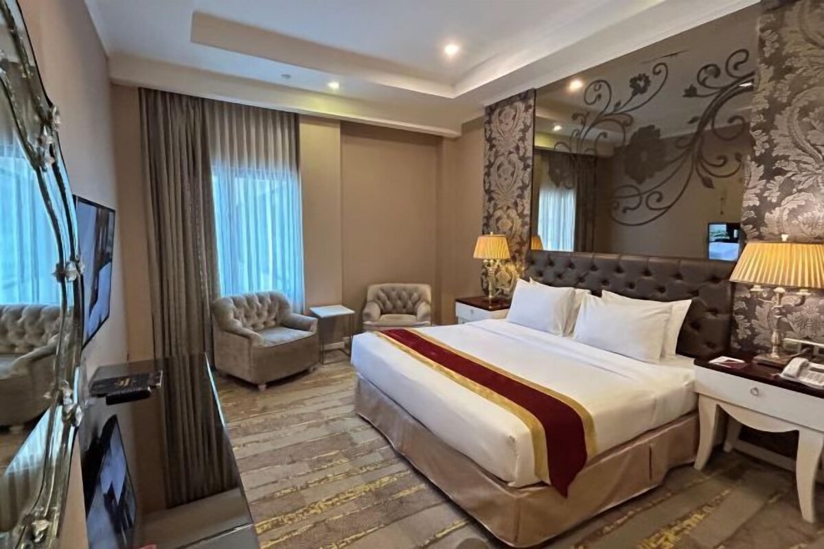 Ein Hotelzimmer mit einem großen Bett, einem Fernseher, einem Schreibtisch und einem Sessel.