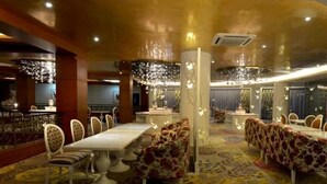 A spacious dining area with a long table, ornate chairs, and decorative lighting. - Sutan Raja Hotel and Convention Cen (Soreang)