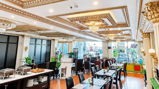 A spacious dining area with high ceilings, ornate gold detailing, and modern furniture.