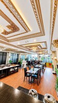 Un comedor espacioso con techos altos, detalles ornamentales en dorado y mobiliario moderno.