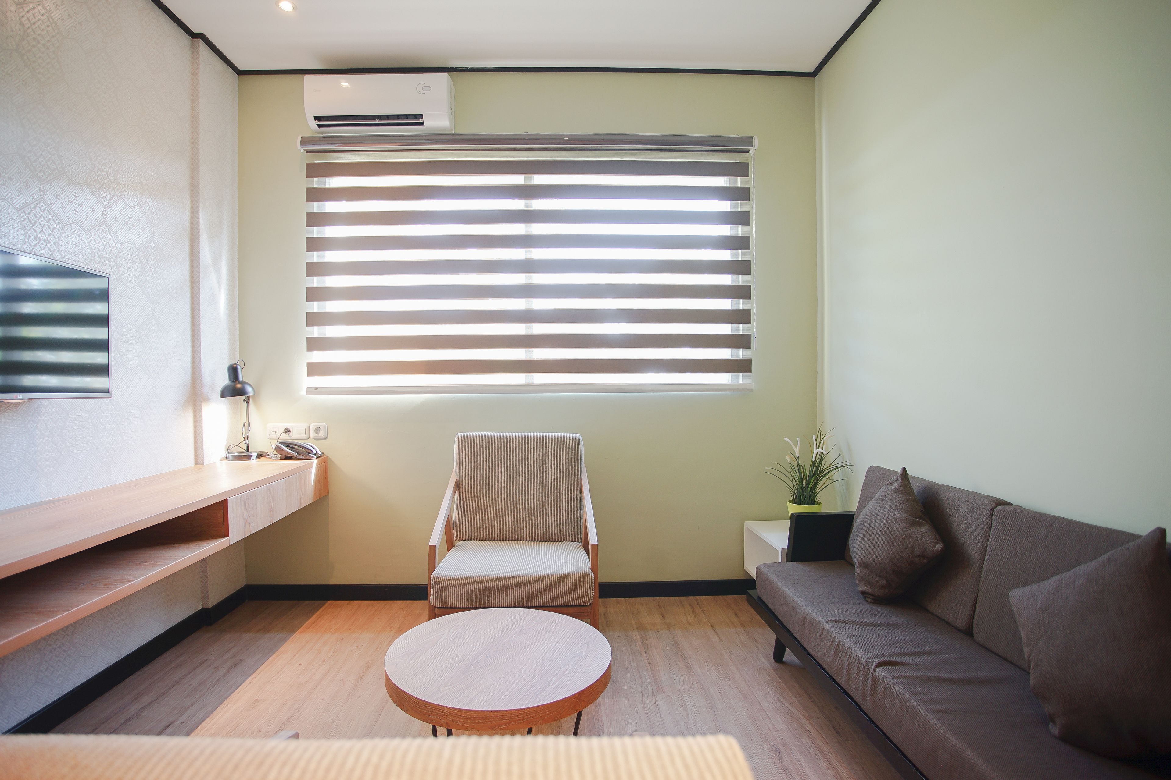 A modern living room with a sofa, a chair, a round coffee table, and a TV mounted on the wall.