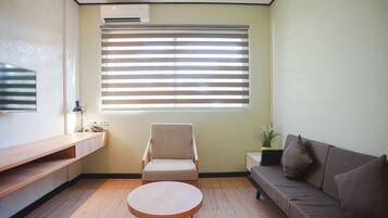 A modern living room with a sofa, a chair, a round coffee table, and a TV mounted on the wall.