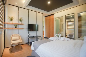 Una habitación de hotel moderna con cama, televisor, silla y armario.