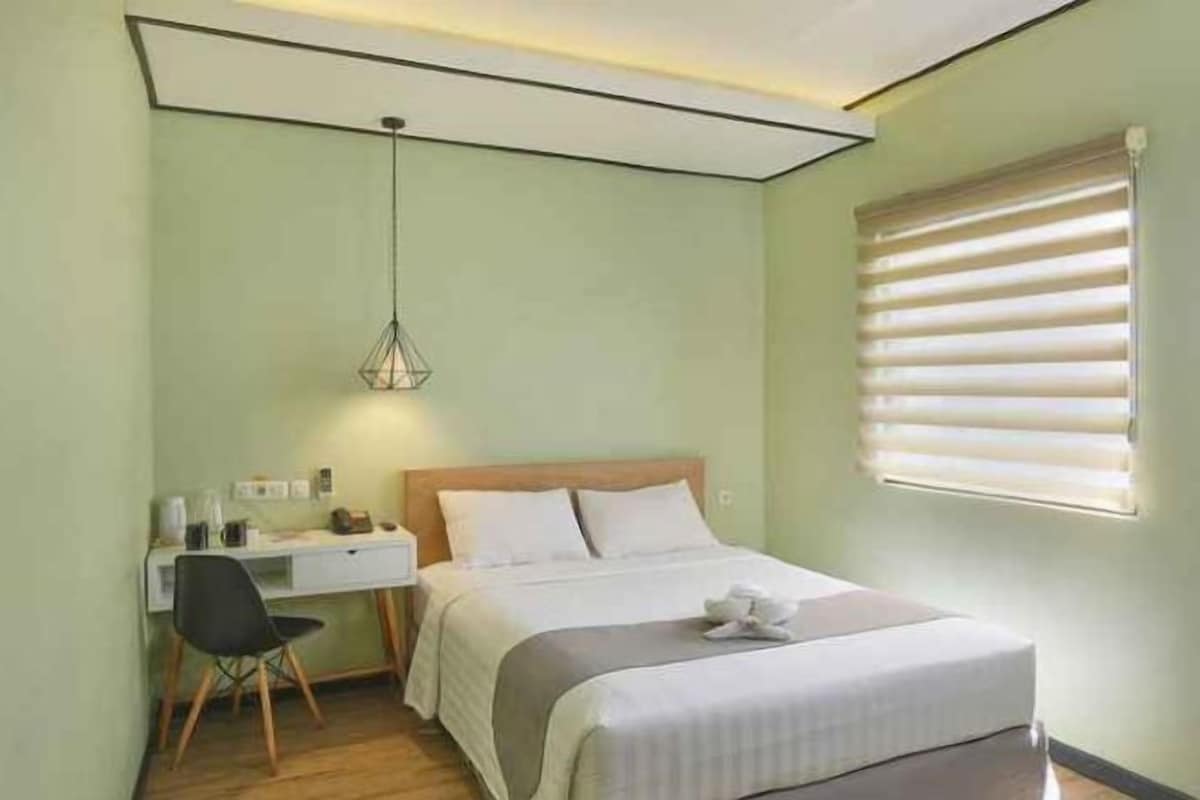 Ein Schlafzimmer mit einem Bett, einem Nachttisch, einem Sessel, einem Schreibtisch und einer Pendelleuchte.