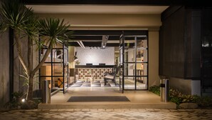 A modern hotel entrance with a tiled floor, a reception desk, a seating area, and a view into the interior. - Allstay Ecotel Yogyakarta (Depok)