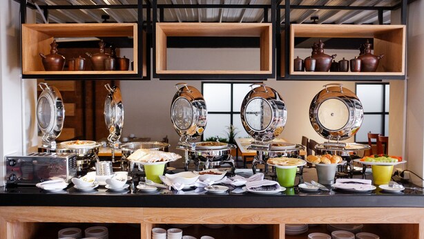 A buffet setup with various food items and serving equipment. - Allstay Ecotel Yogyakarta (Depok)