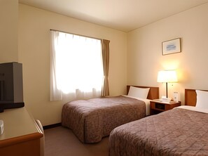 Habitación de hotel con dos camas, un escritorio, un televisor y una ventana con cortinas.