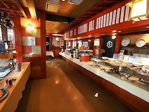 Disposición de tipo bufé con diferentes estaciones de comida y una zona de bar.