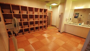A bathroom with a wooden floor, a fan, a sink, and shelves with baskets.