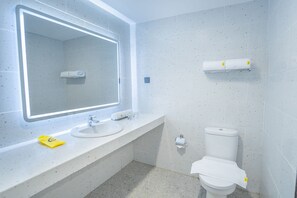 Une salle de bain moderne avec un grand miroir, un lavabo, des toilettes et un porte-serviettes.
