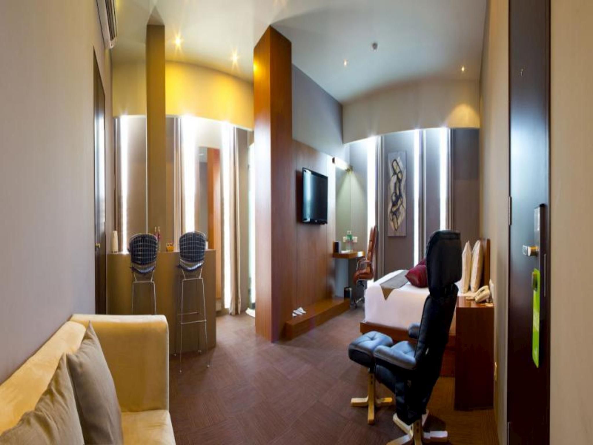 A hotel room with a bed, a desk, a chair, a television, and a large mirror.