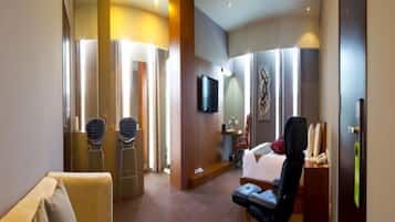 A hotel room with a bed, a desk, a chair, a television, and a large mirror.
