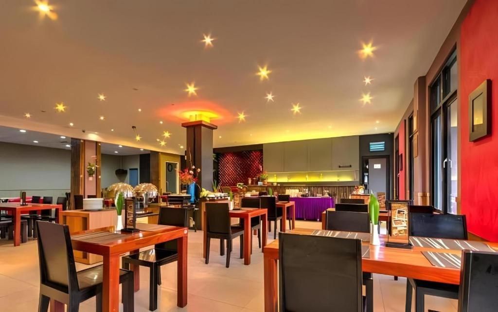 A restaurant with multiple dining tables and chairs, a kitchen area in the background, and a ceiling with star-shaped lights.