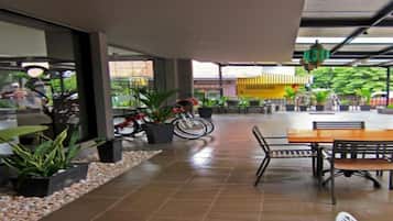 An outdoor patio area with a dining table and chairs, potted plants, and a bicycle.