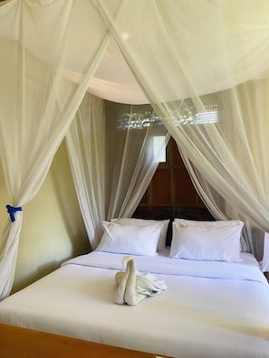 Un lit avec du linge de lit blanc, un baldaquin blanc et une serviette sur le lit.