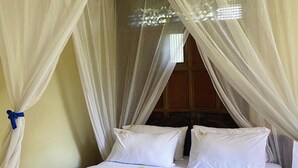 A bed with white linens, a canopy, and a towel on the bed.