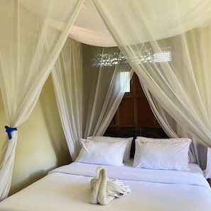 A bed with white linens, a canopy, and a towel on the bed.